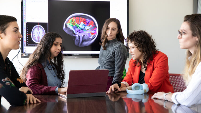 Various individuals discuss in a meeting room on a brain scan.