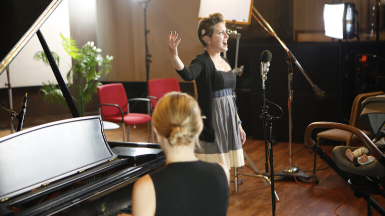 Women singing in room with accompanying piano