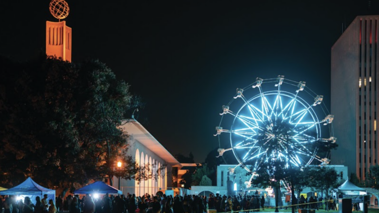 A festival on campus with a ferris wheel at night.