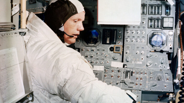 Neil Armstrong trains in the lunar module simulator in full space uniform.