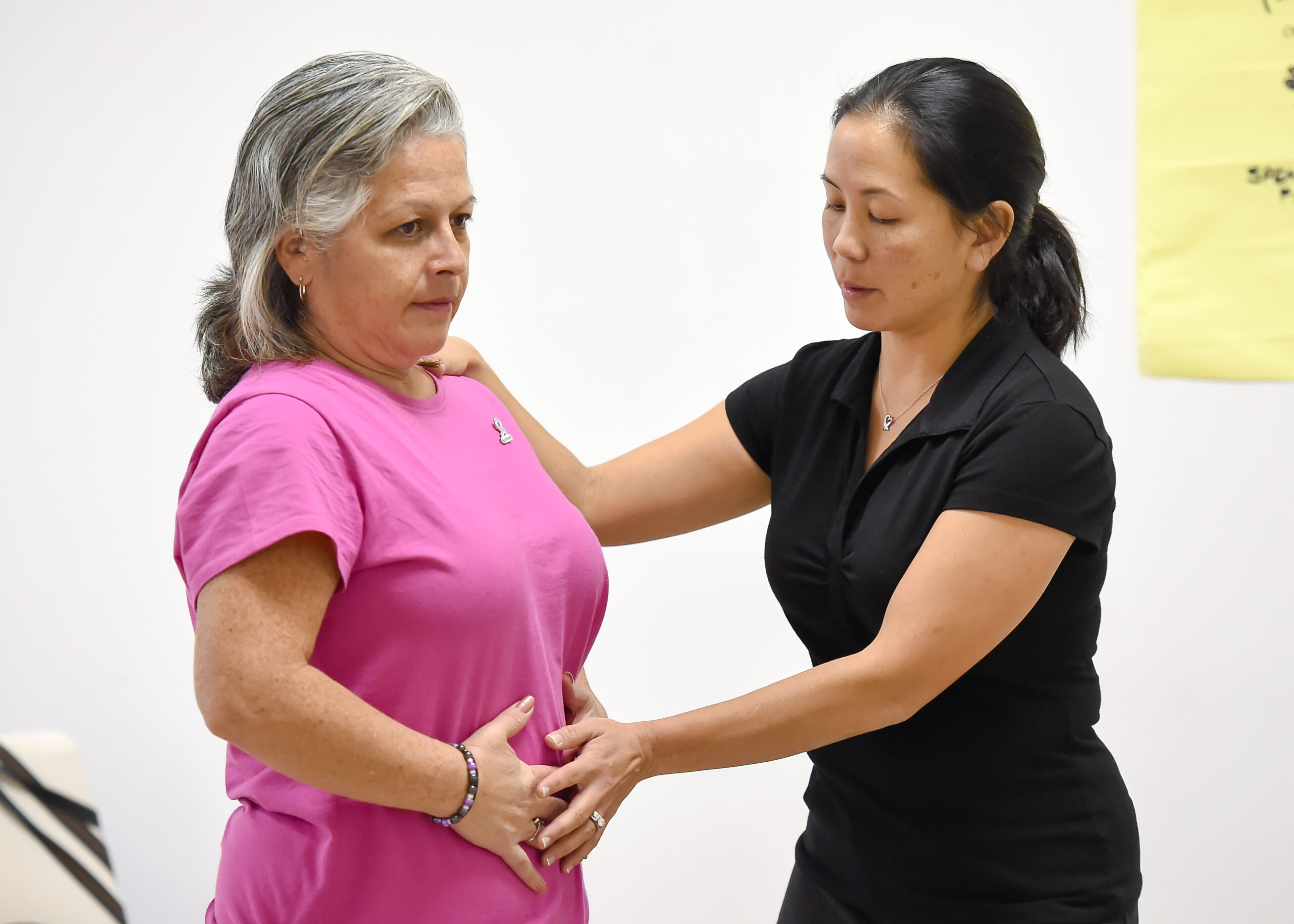 Instructor working with class attendee during free exercise class for cancer survivors