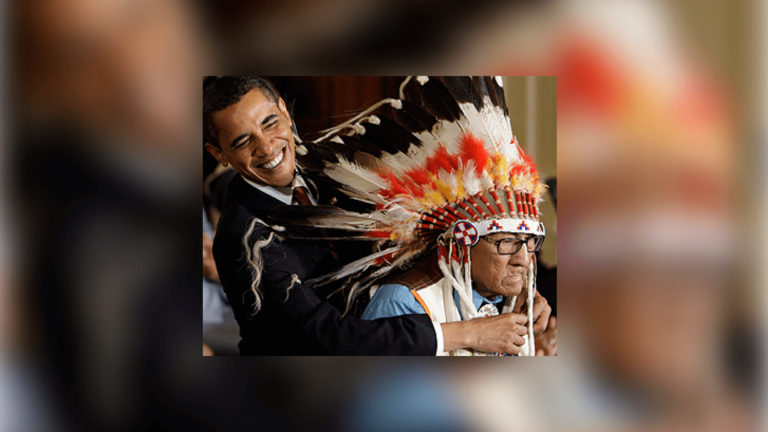 President Barack Obama reaches around the headdress of Chief Joseph Medicine Crow to place a 2009 Presidential Medal of Freedom.
