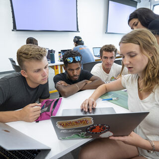 Students from the USC Iovine and Young Academy work together in a group around a computer.