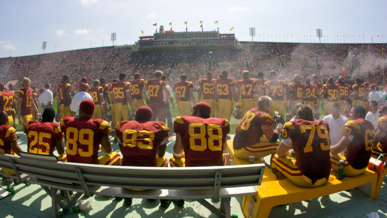Members of USC's Trojan Football team gather along the sidelines before entering the game.