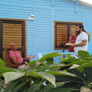 Two USC students interview a man outside his home for their research
