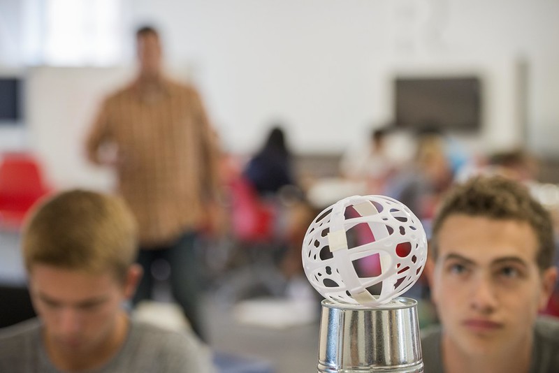 Students stare at white plastic globe on top of a cylinder silver container