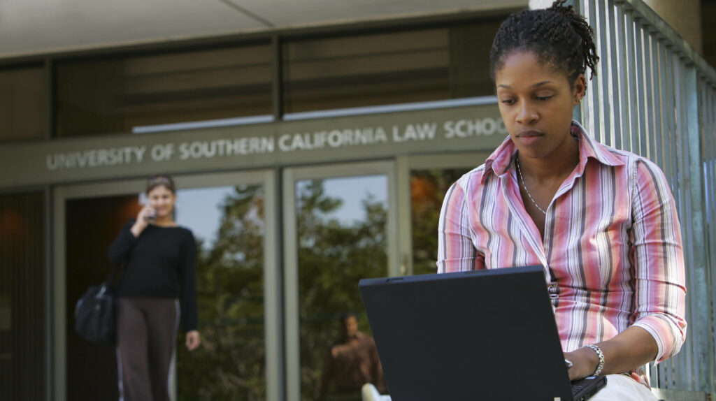 Student on laptop outside of law school
