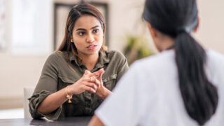 Two women sit talking at a table