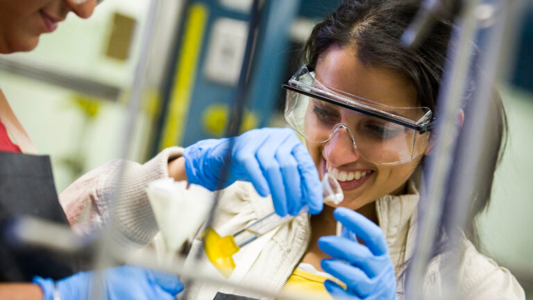A USC researcher smiles while working with lab materials